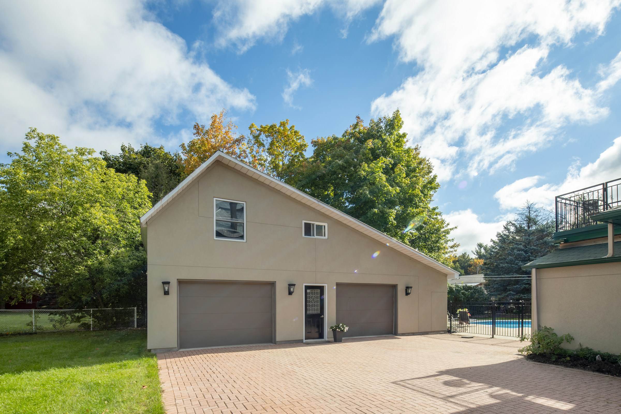 A beige house with a two-car garage and a paved driveway, the kind of outbuilding where rodents look for shelter.