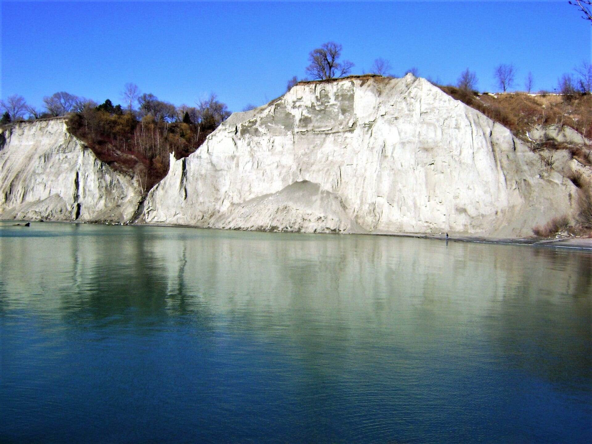 The white cliffs of the Scarborough Bluffs above the still water of Lake Ontario.