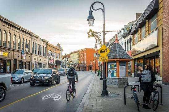 A downtown St. Catharines street with shops, a cyclist in the bike lane and a lamp post with a star decoration.